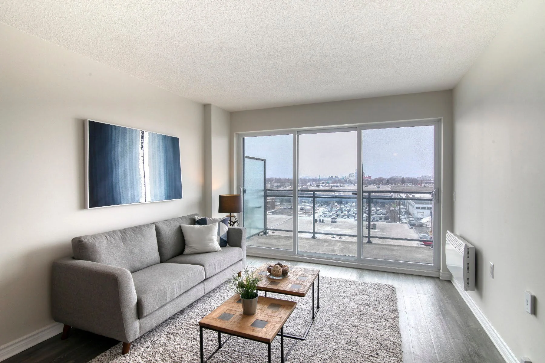 Salon lumineux avec porte-fenêtre donnant sur un balcon dans un appartement témoin de la Résidence Le Parc, à Saint-Léonard