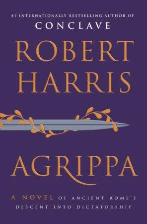 Cover of the book 'Agrippa' by Robert Harris showing purple background with gold text and a decorative ornamental element.