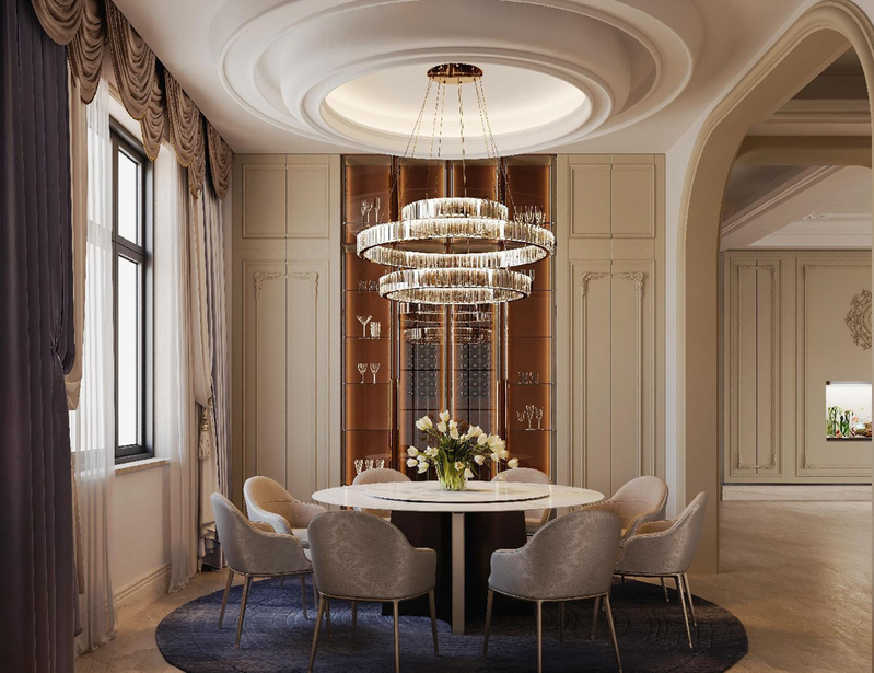 Elegant dining room with a round table, eight upholstered chairs, a large chandelier, vase with flowers, large window with drapes, and built-in wooden cabinets.
