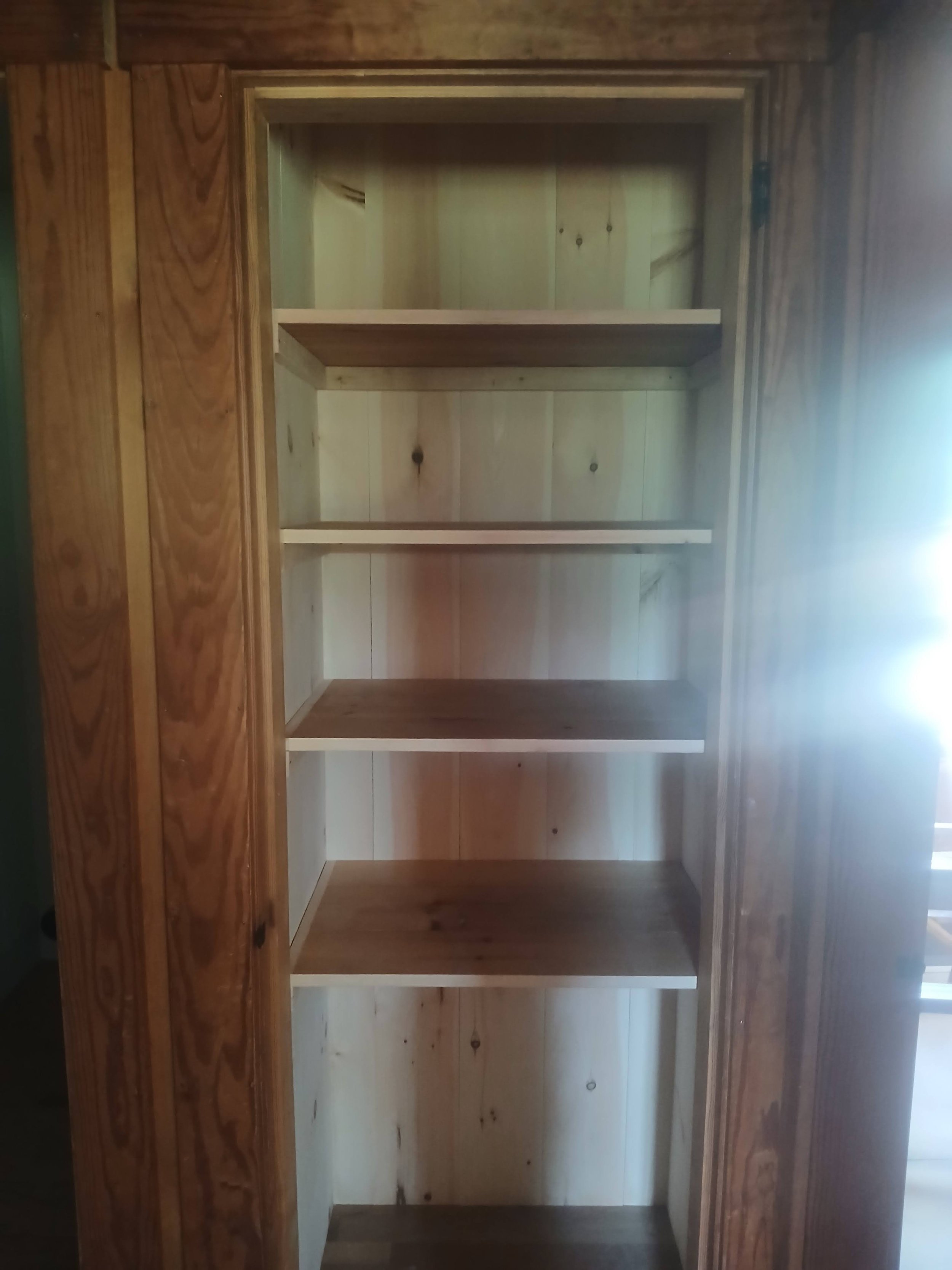 Empty wooden bookshelf with five shelves in a room.