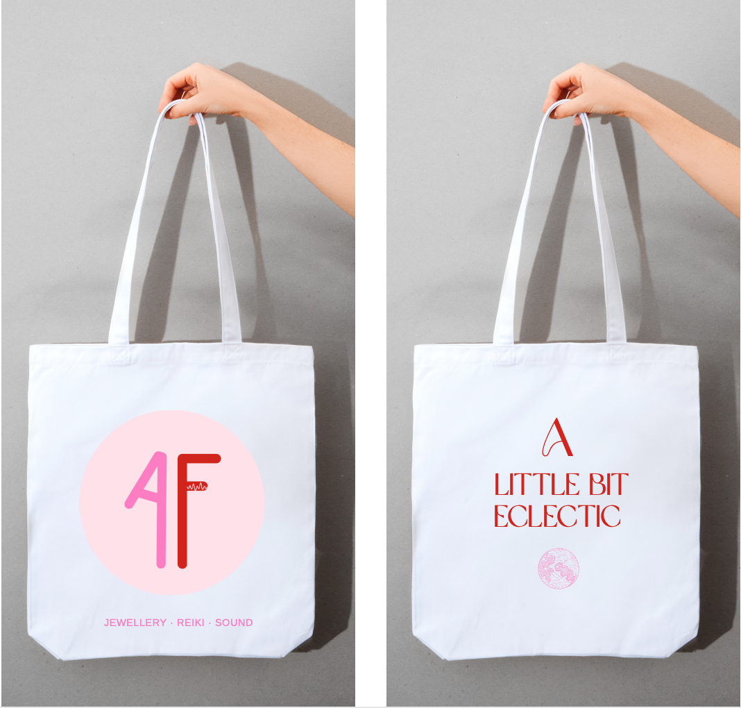 Two white tote bags held against a gray background. The left bag features a pink circle with stylized pink and red lettering and small text that reads 'Jewellery, Reiki, Sound.' The right bag displays red text that says 'A Little Bit Eclectic' with a small pink circular design below.