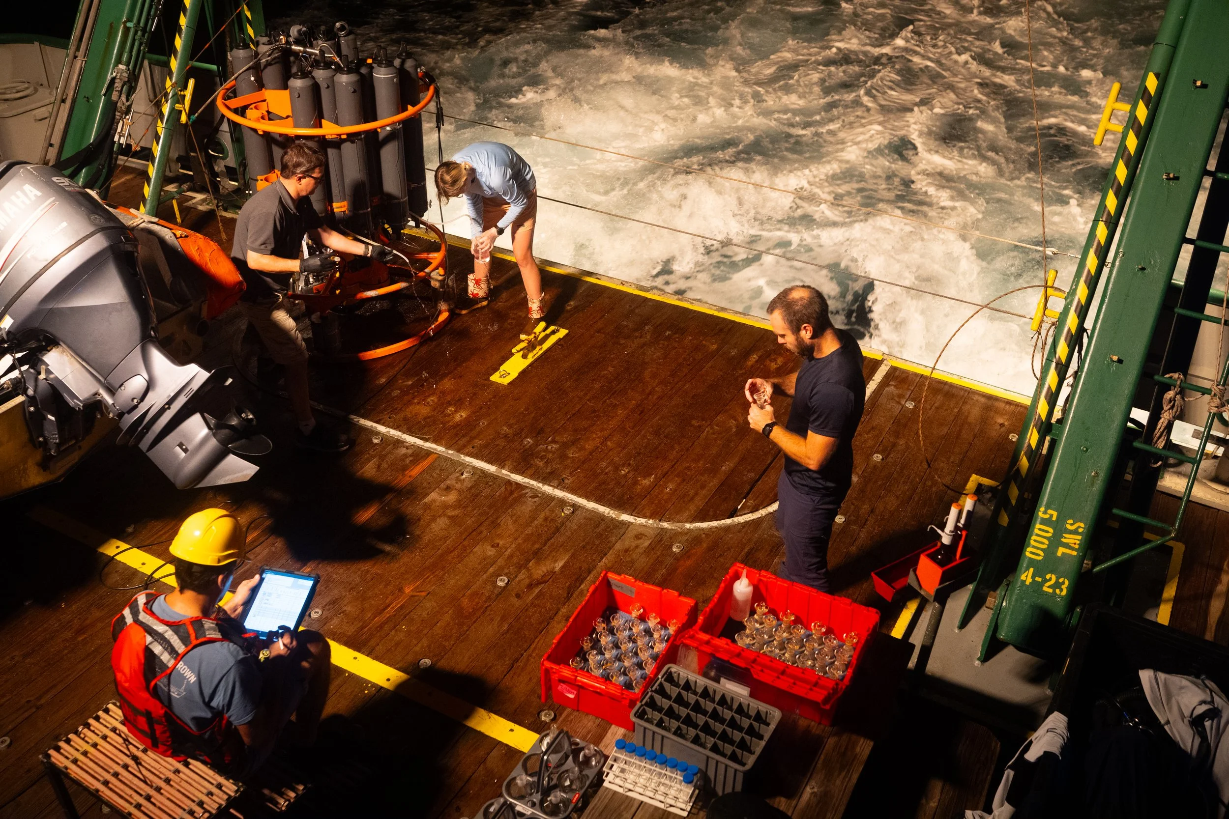 Scientists collect water samples from a recovered instrument in the early morning hours. From left are Denis Volkov, bottom, Ryan H. Smith, Tyler Christian, and Jay Hooper.
