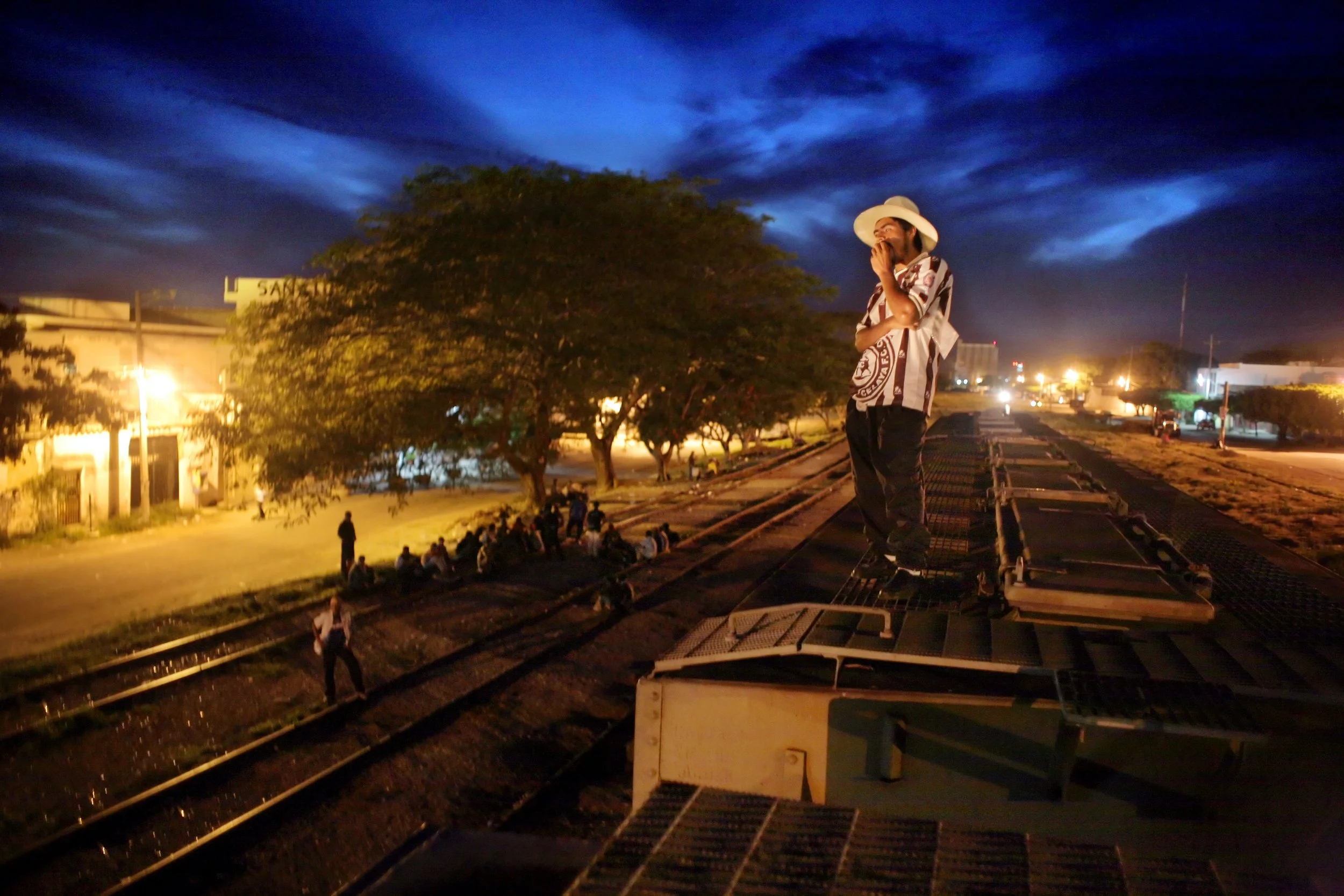Hernan Enriquez, 25, of Honduras rides atop a freight train in Arriaga, Chiapas, Mexico, May 27, 2006. Traveling alone, he left home eight days earlier in search of a better life in the United States.