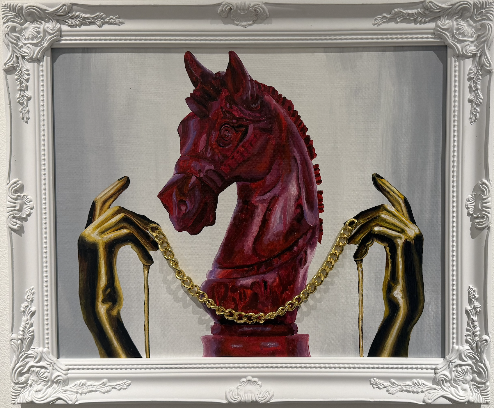 Painting of a red horse head sculpture with gold hands holding a gold chain in front of a white ornate frame.
