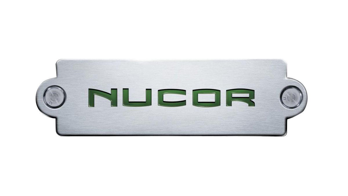 Close-up of a metallic panel with the word 'NUCOR' engraved in green letters. This is the Nucor logo.