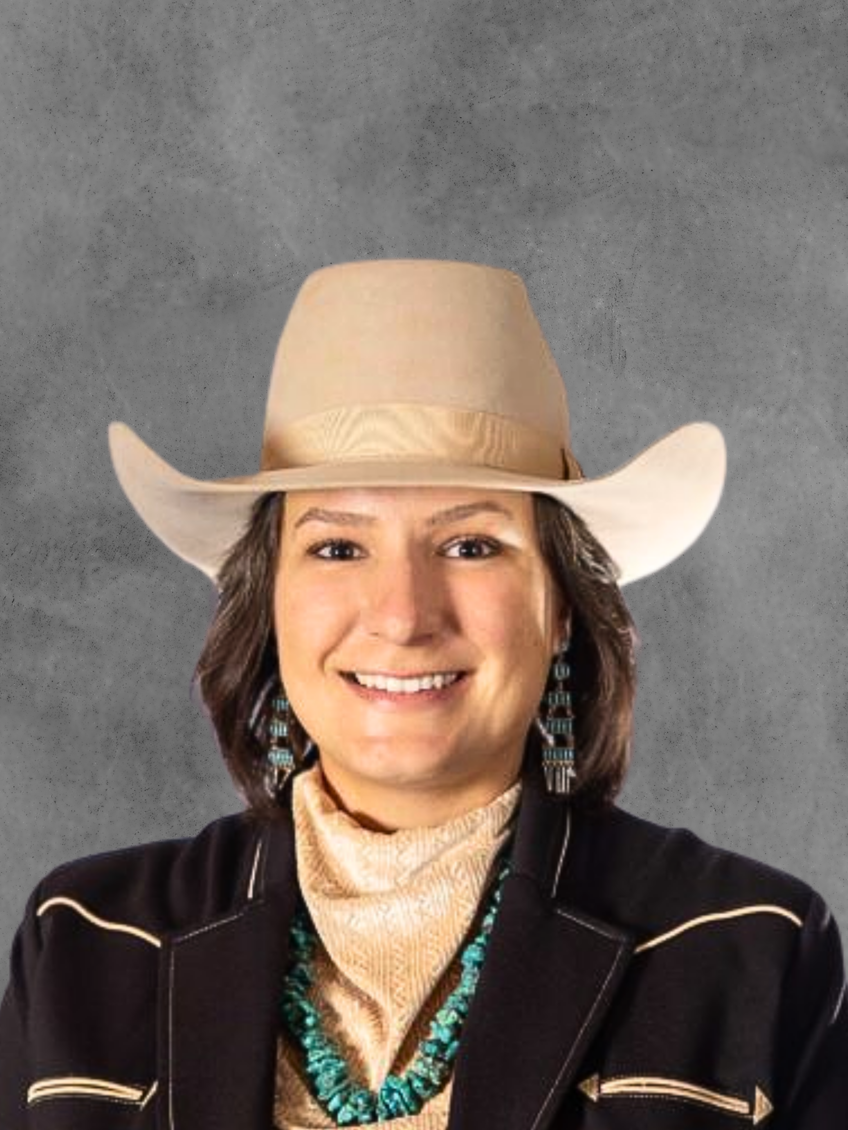 Woman wearing a cowboy hat, earrings, and a western-style outfit, smiling against a gray background.