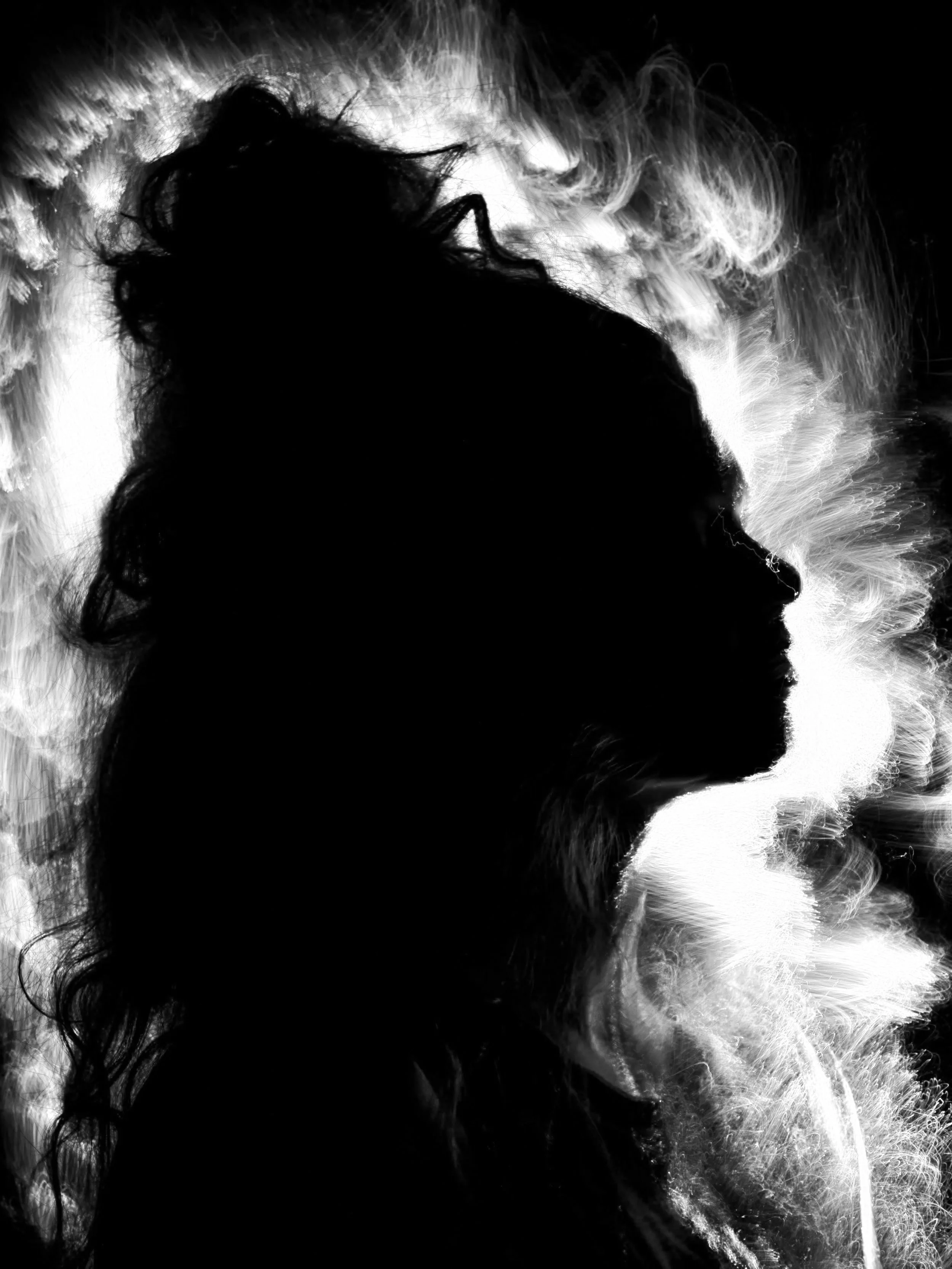 Black and white silhouette of a woman's profile with curly hair against a smoky, abstract background.