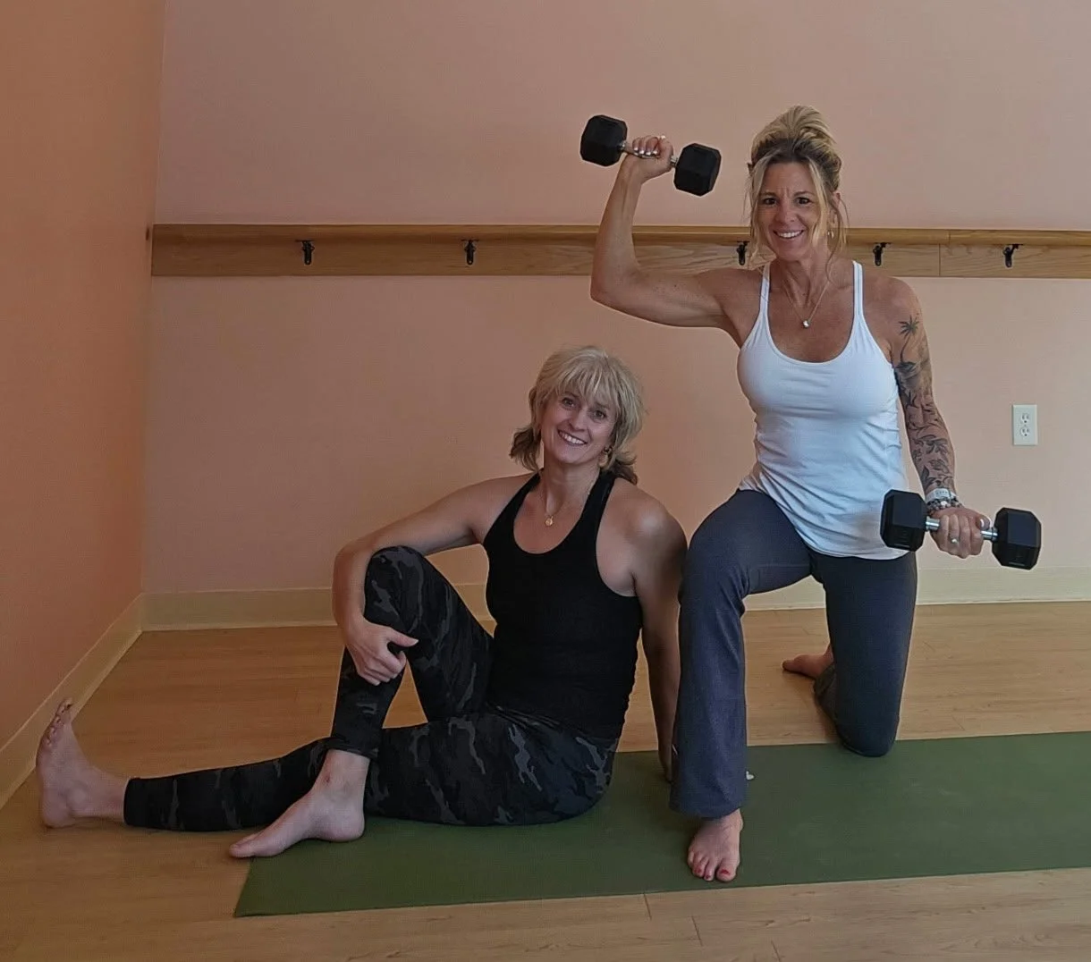 Shari and Tracey posing on yoga mat with weights.