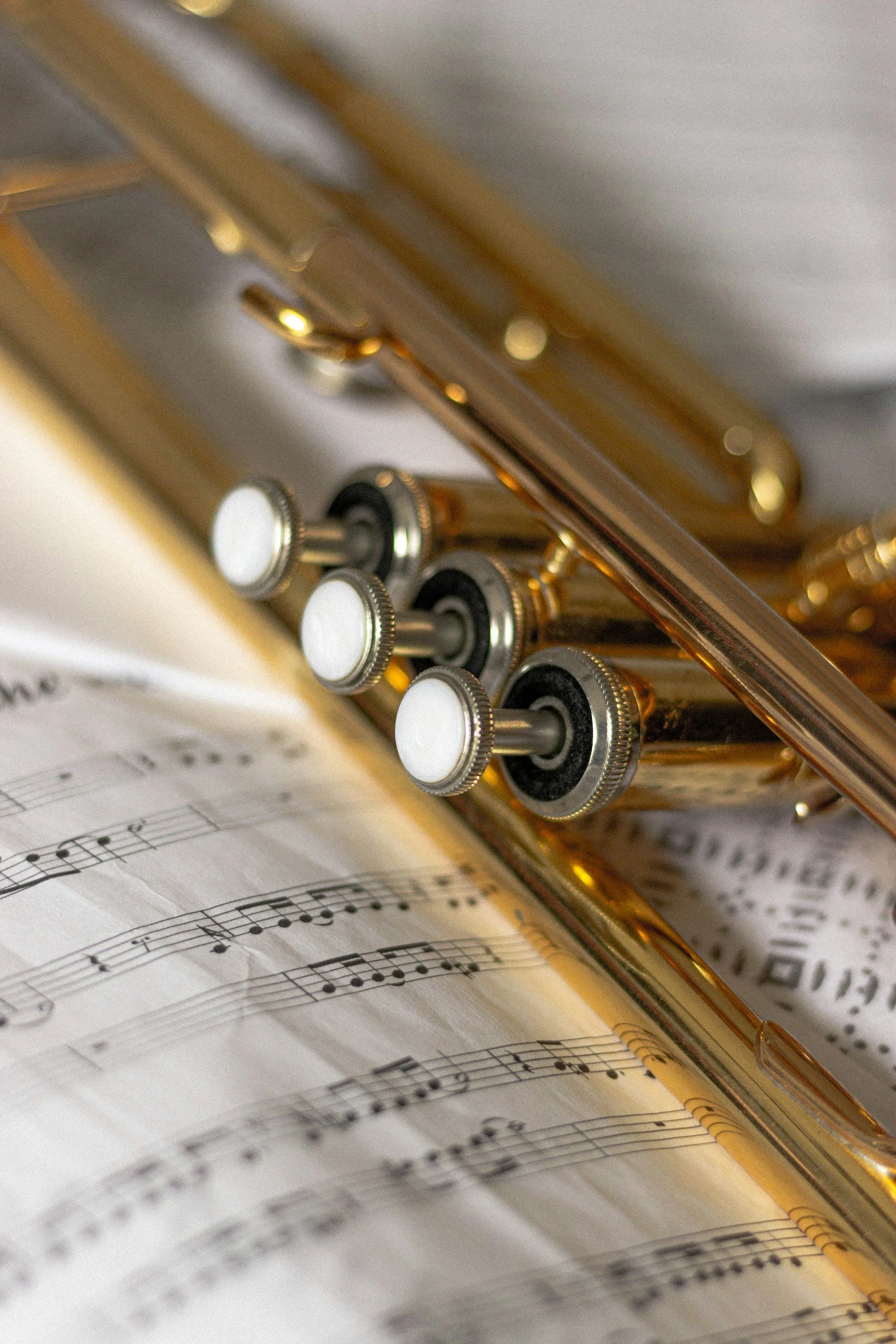 Close-up of a gold trumpet lying on sheet music.