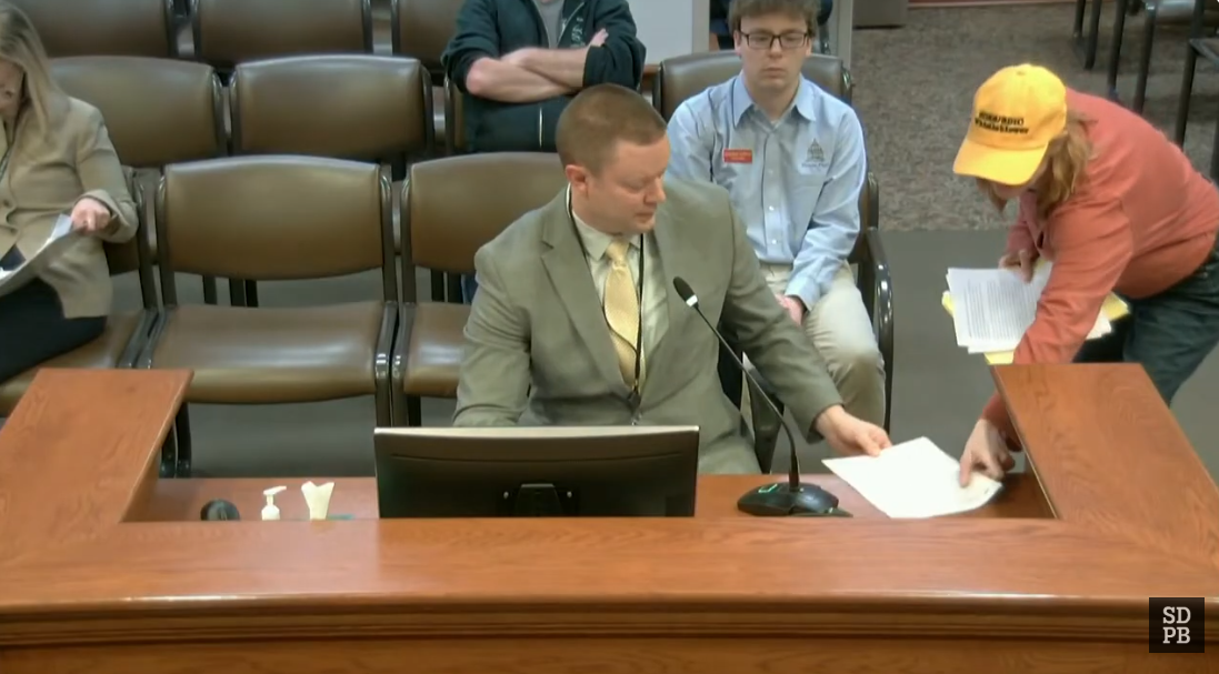 Renae Randall with yellow "SDRS/SDIC Whistleblower" hat showing John Richter the IRS forms of possible IRS violation by the SDIC