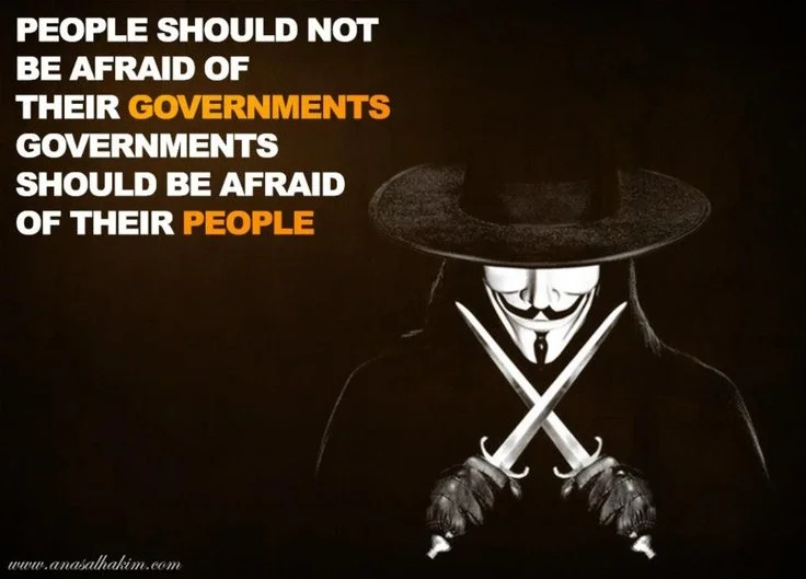 A person dressed as the vigilante character V from V for Vendetta, wearing a Guy Fawkes mask and black costume with gloves, holding two crossed knives. The background is black with white and orange text that reads, 'People should not be afraid of their governments. Governments should be afraid of their people.'