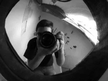 Un homme prenant une photo de lui-même dans un miroir en utilisant un appareil photo.