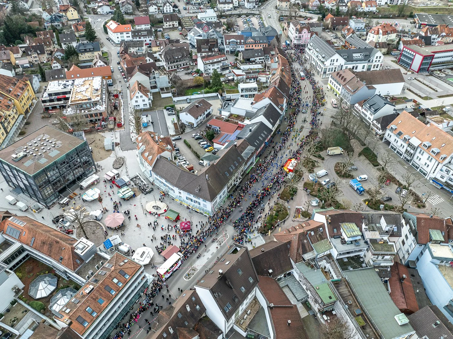 Luftaufnahme einer Innenstadt mit Menschenmengen, Geschäften, Parkplätzen und Straßen im Winter