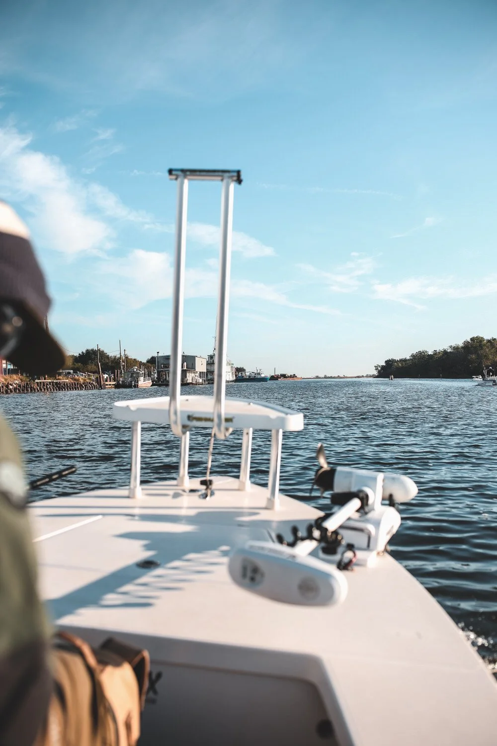 A boat on a body of water, with a clear blue sky and a distant shoreline with trees and buildings.