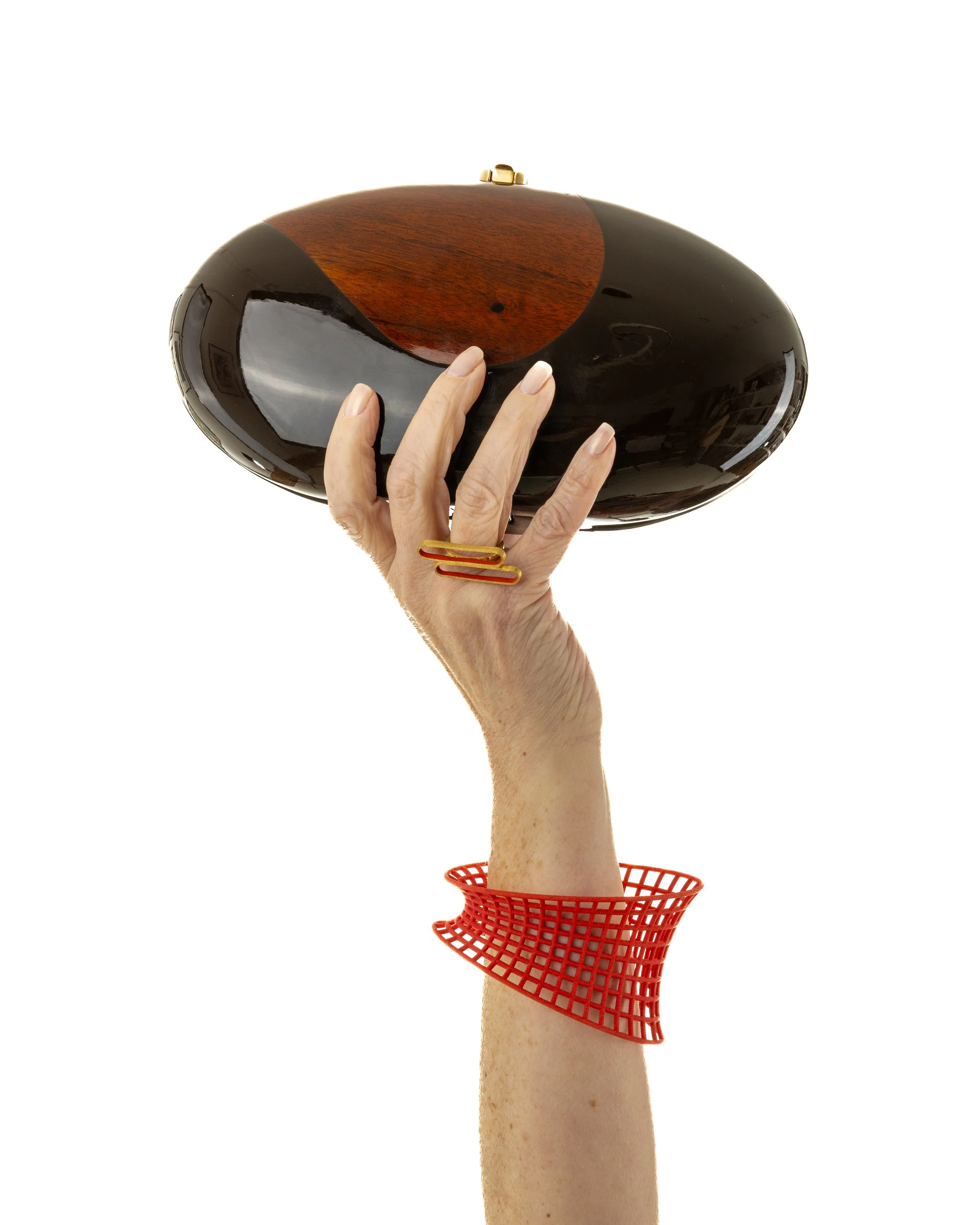 Elegant Hand holding a Rocio Oscar Clutch, Marta Riberio Ring and a Maria Eife Bangle on a white background