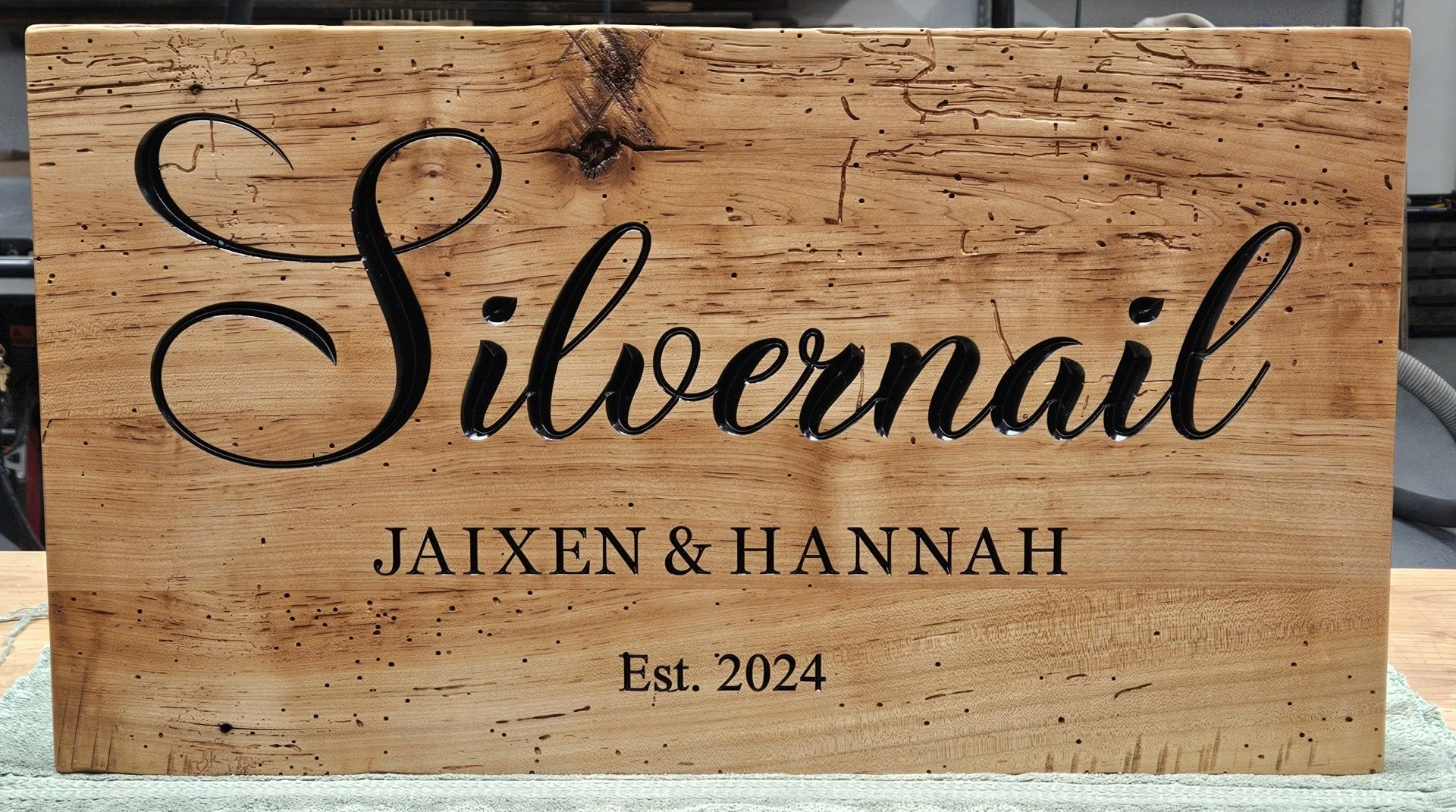 Wooden sign with the word 'Silvernail' in black cursive and 'JAIXEN & HANNAH Est. 2024' in black uppercase and lowercase font.