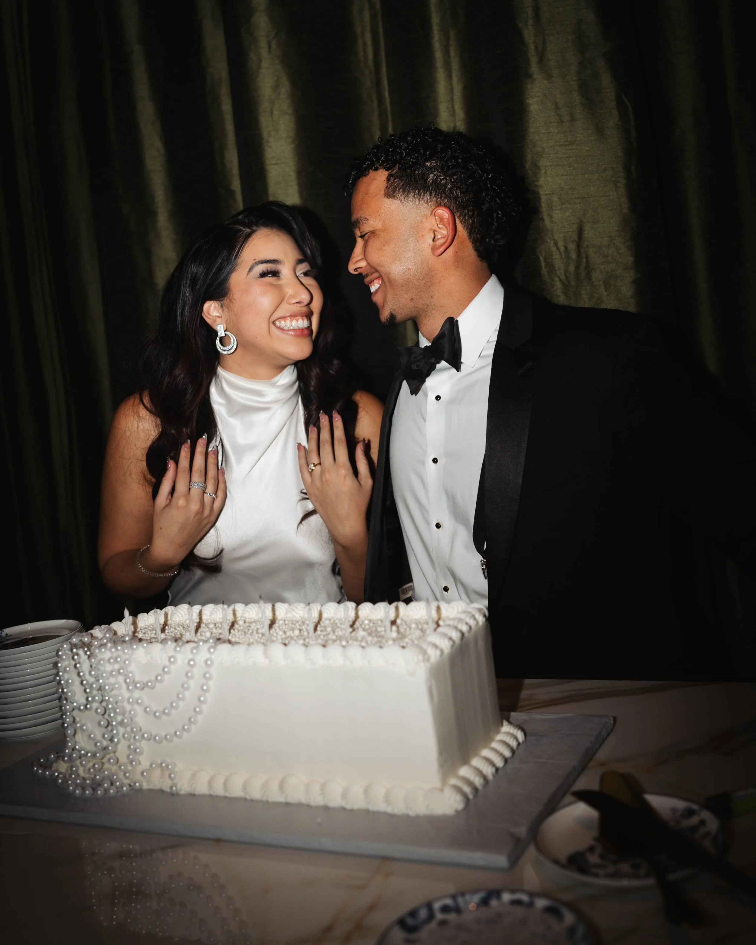 A happy couple, dressed in formal attire, celebrating with a wedding cake at a special event.