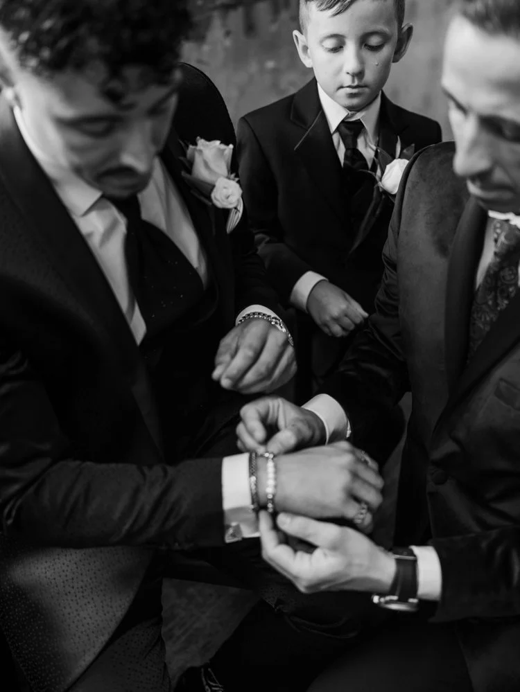 A groom and groomsmen in suits exchanging rings while the ring bearer watches at a luxury hotel Wedding 