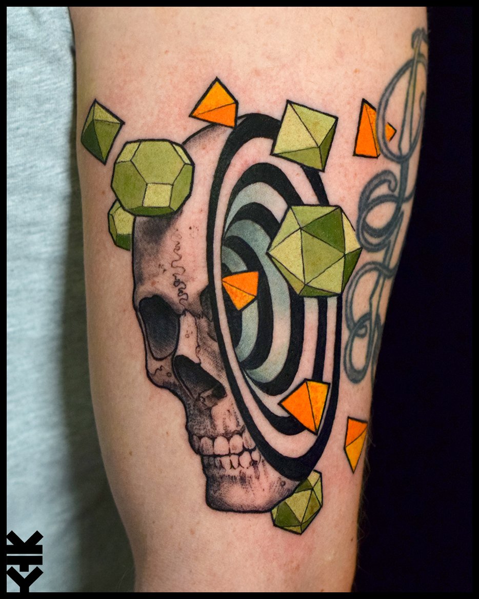 Tattoo of a human skull with geometric shapes and spiral. Green, orange, and yellow 3D polyhedrons scattered around.