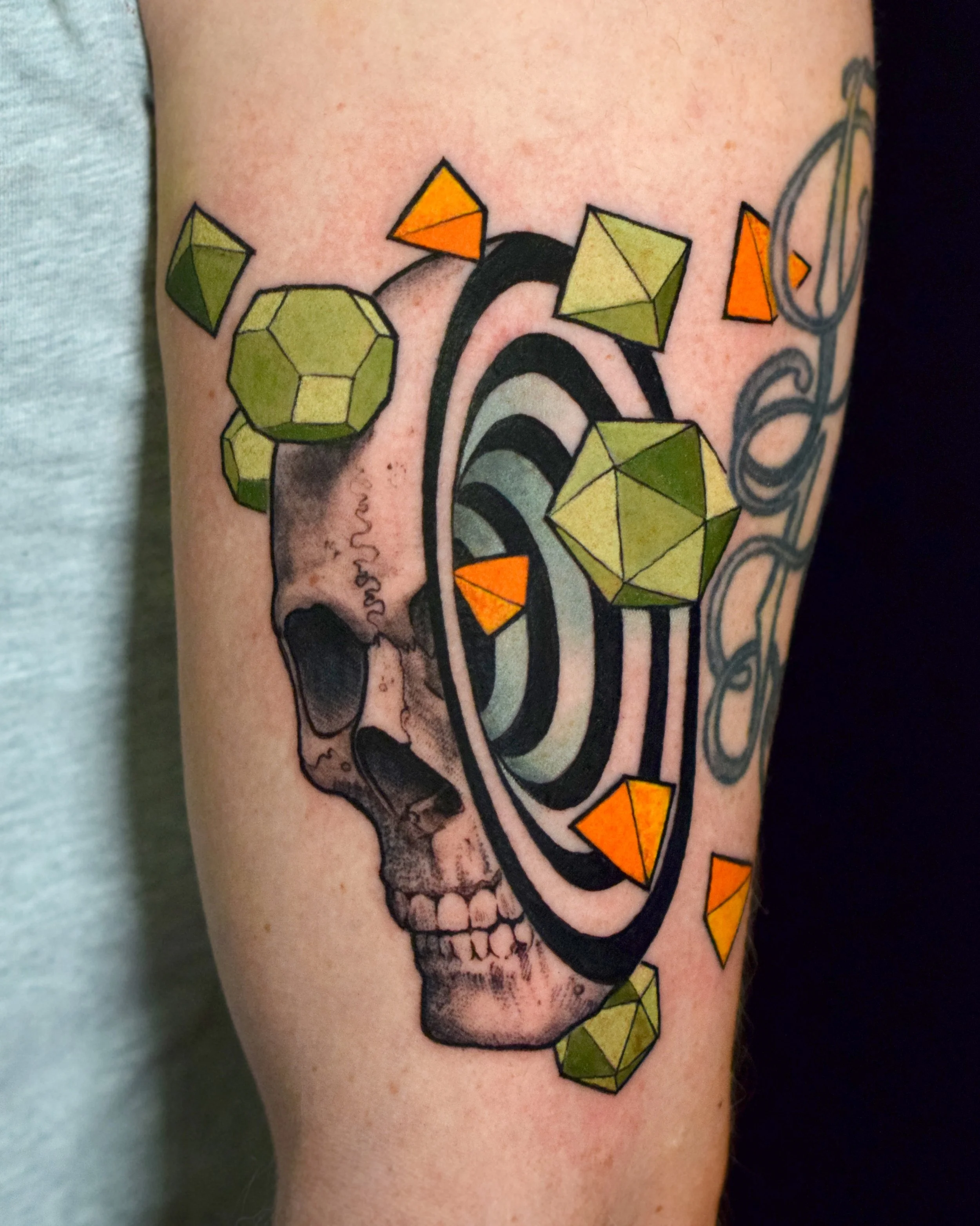 Tattoo of a human skull with geometric 3D shapes and a vortex pattern above it.