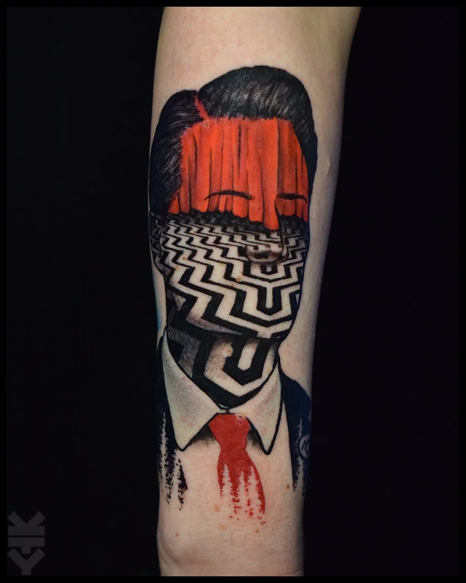 Tattoo of a person's head with a red curtain in place of facial features, on a black and white maze pattern face, dressed in a suit with a red tie, with blood dripping from the tie. twin peaks