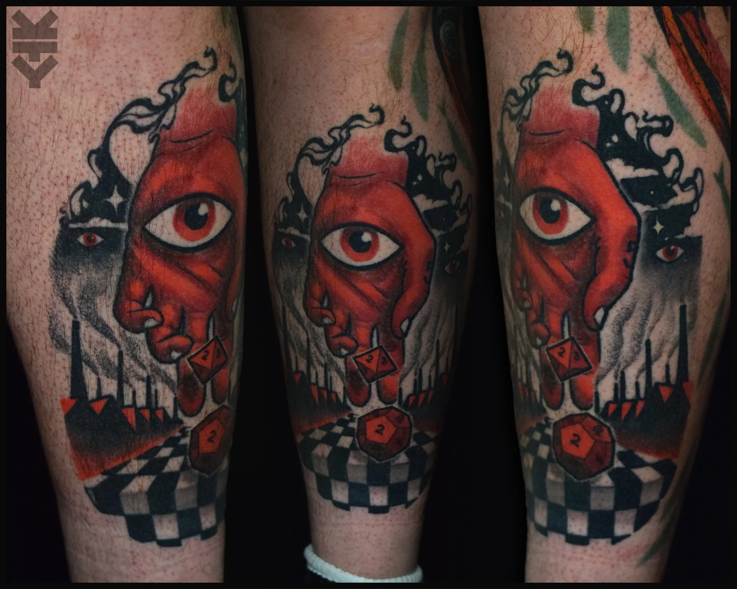Tattoo of a surreal woman's face with large eye, surrounded by abstract patterns, dice, and checkerboard designs in red, black, and white.
