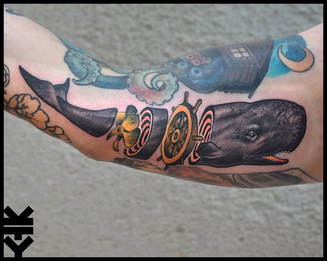 Tattoo of a black dog with an open mouth on a person's arm, featuring sunglasses and a ship's steering wheel.
