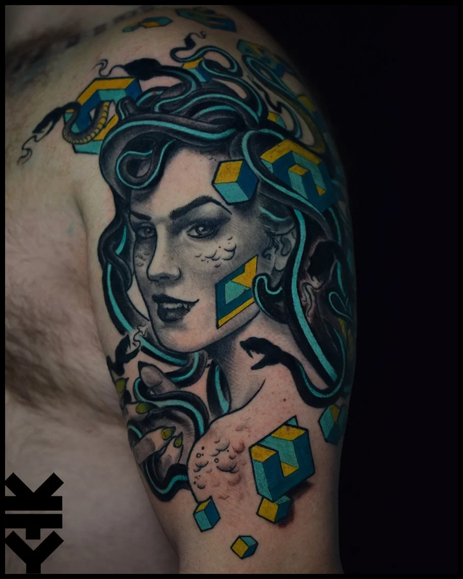 Tattoo of a woman with snake-like hair, cartoon cubes, and detailed shading on upper arm.