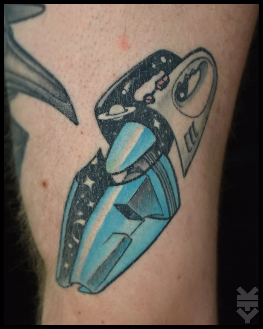 Tattoo of a soda can opening with the phrase "CLIC", and a space-themed submarine with planets and stars depicted inside.