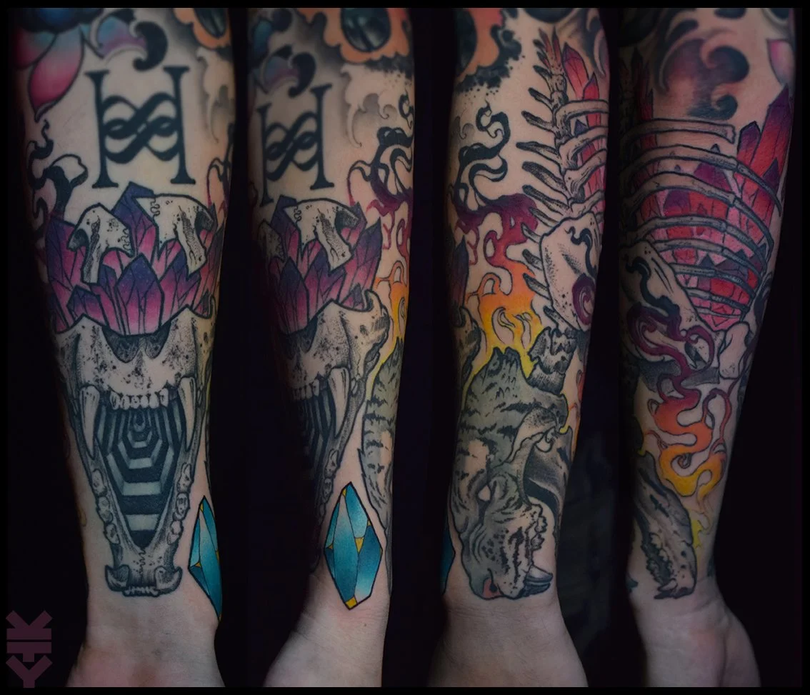 Tattoo sleeves on four arms featuring skulls, crystals, mountains, and animal skulls with flames, using bold black outlines and vibrant colors.