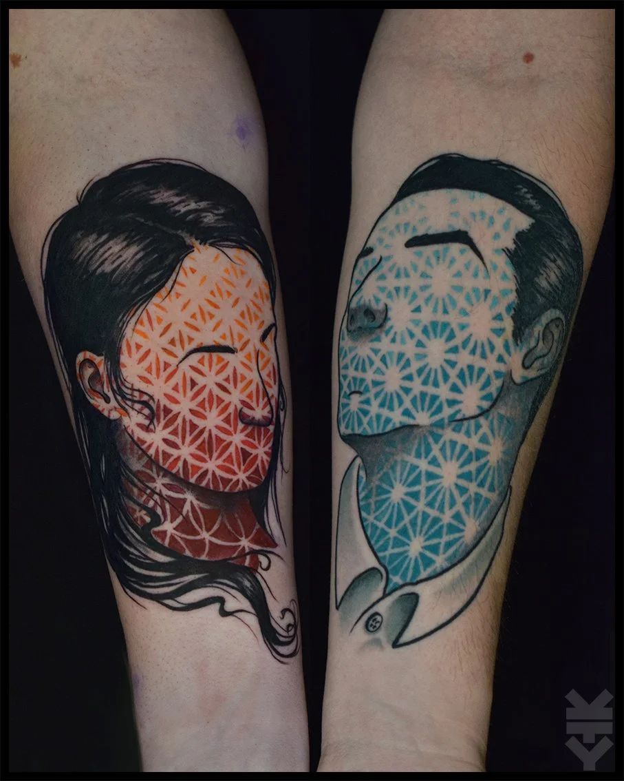 Tattoo of two faces with geometric pattern faces, one female with long hair and one male with short hair, in black ink with red and blue coloring.
