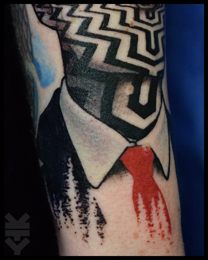 Tattoo of a man's shirt collar and tie, with a black and white maze-like pattern on the face, and blood dripping from the tie. twin peaks