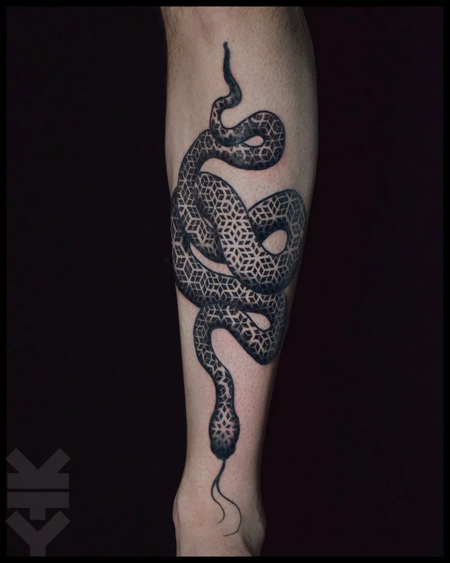 A tattoo of a black snake with geometric patterns on its body, coiled around the lower leg.