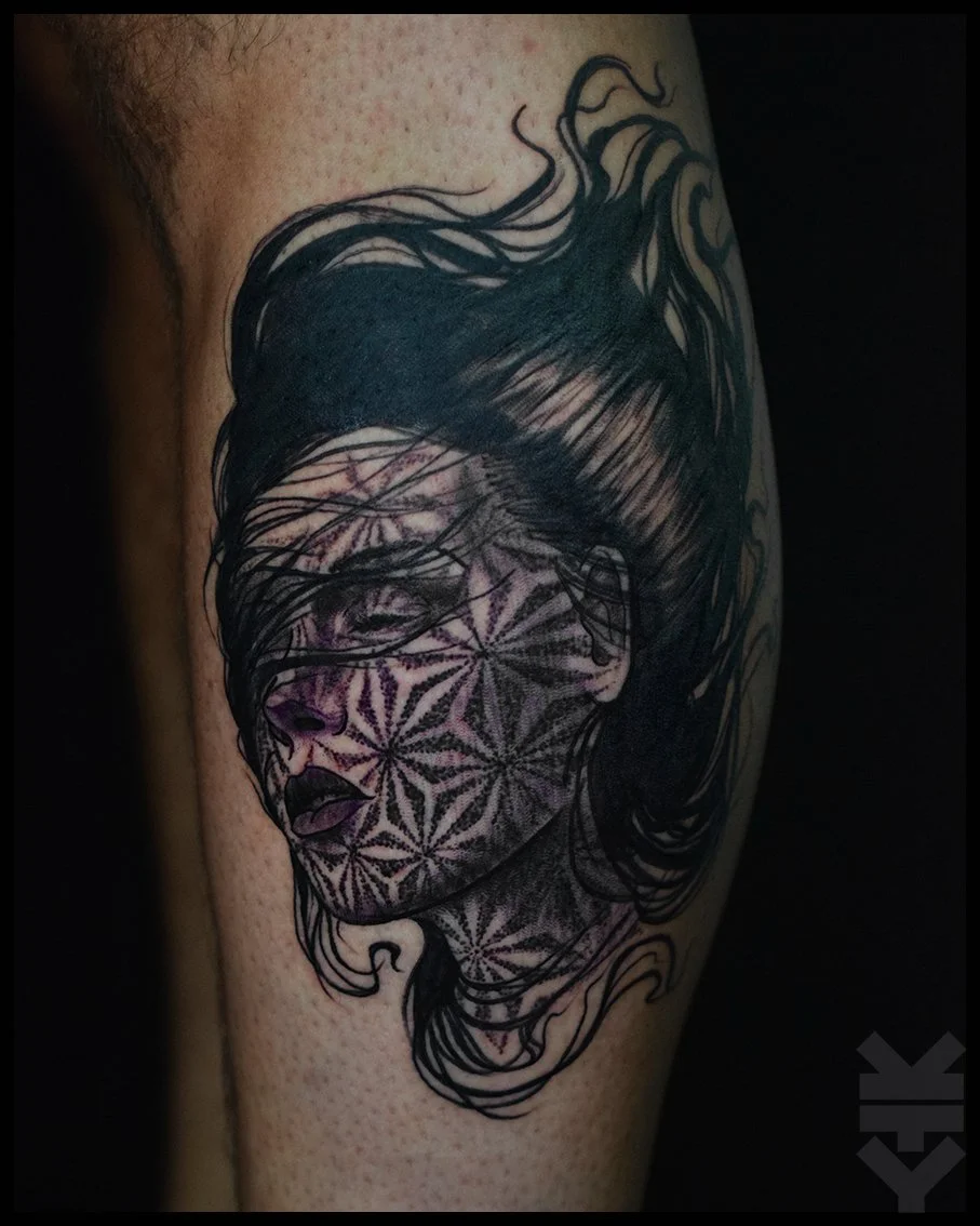 Tattoo of a woman's face with flowing hair and geometric patterns on her face and neck.