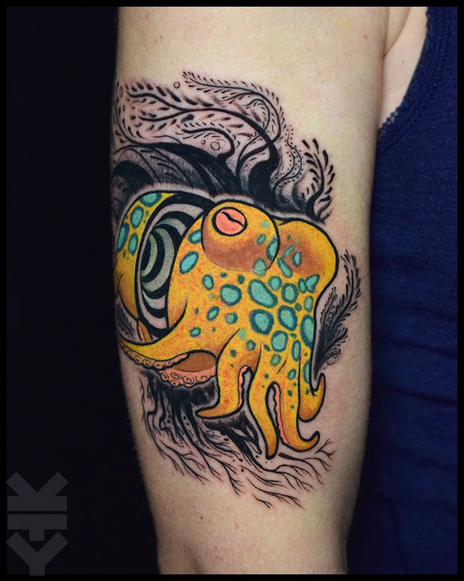 Colorful tattoo of a yellow octopus with blue spots, surrounded by black abstract lines and swirls on upper arm.