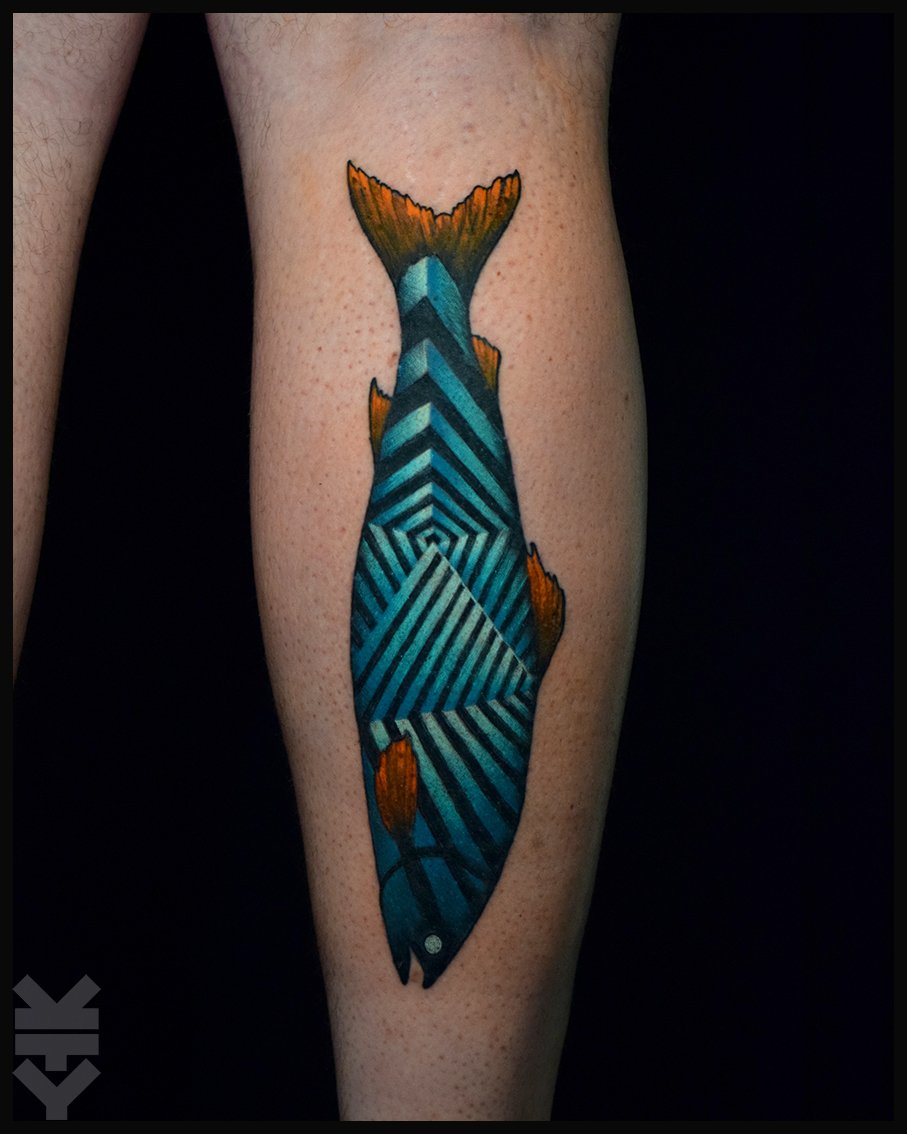 A colorful tattoo of a fish with geometric blue and black striped patterns and orange fins on a person's calf.