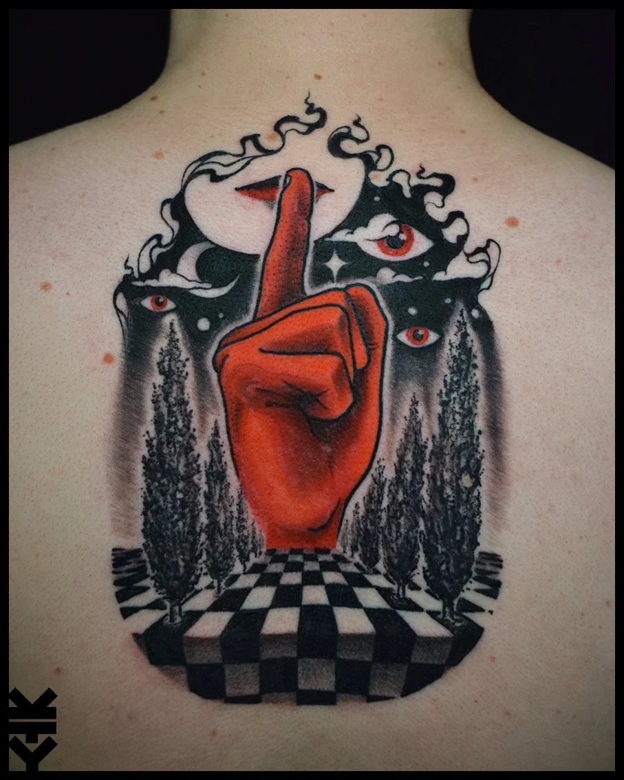 Tattoo on person's chest featuring a large red hand with the index finger raised to lips, surrounded by eyes, smoke, a black and white checkered floor, and trees.