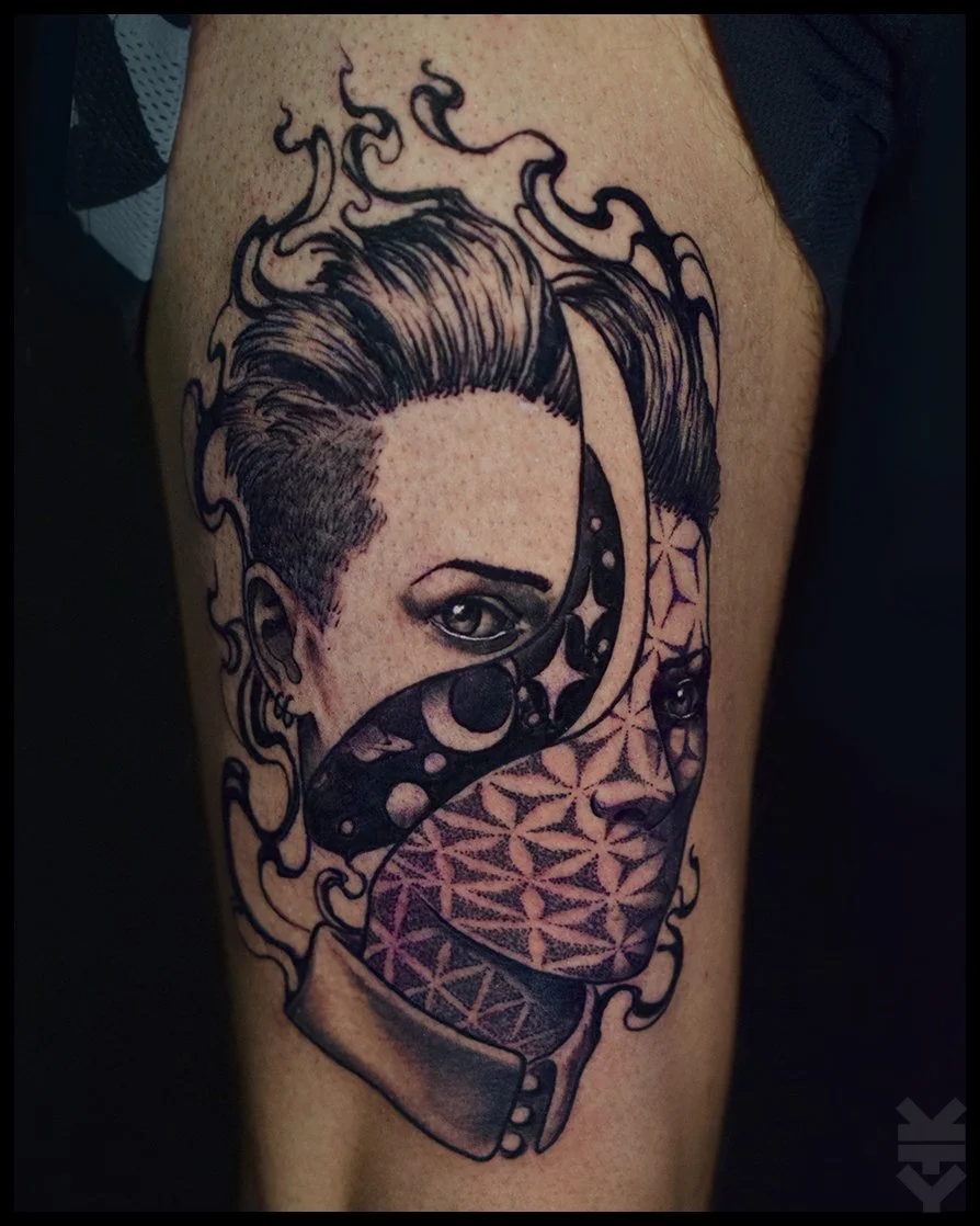 Tattoo of a woman with short hair and one eye visible, partially covered by a patterned mask, with swirling smoke or hair around her head.