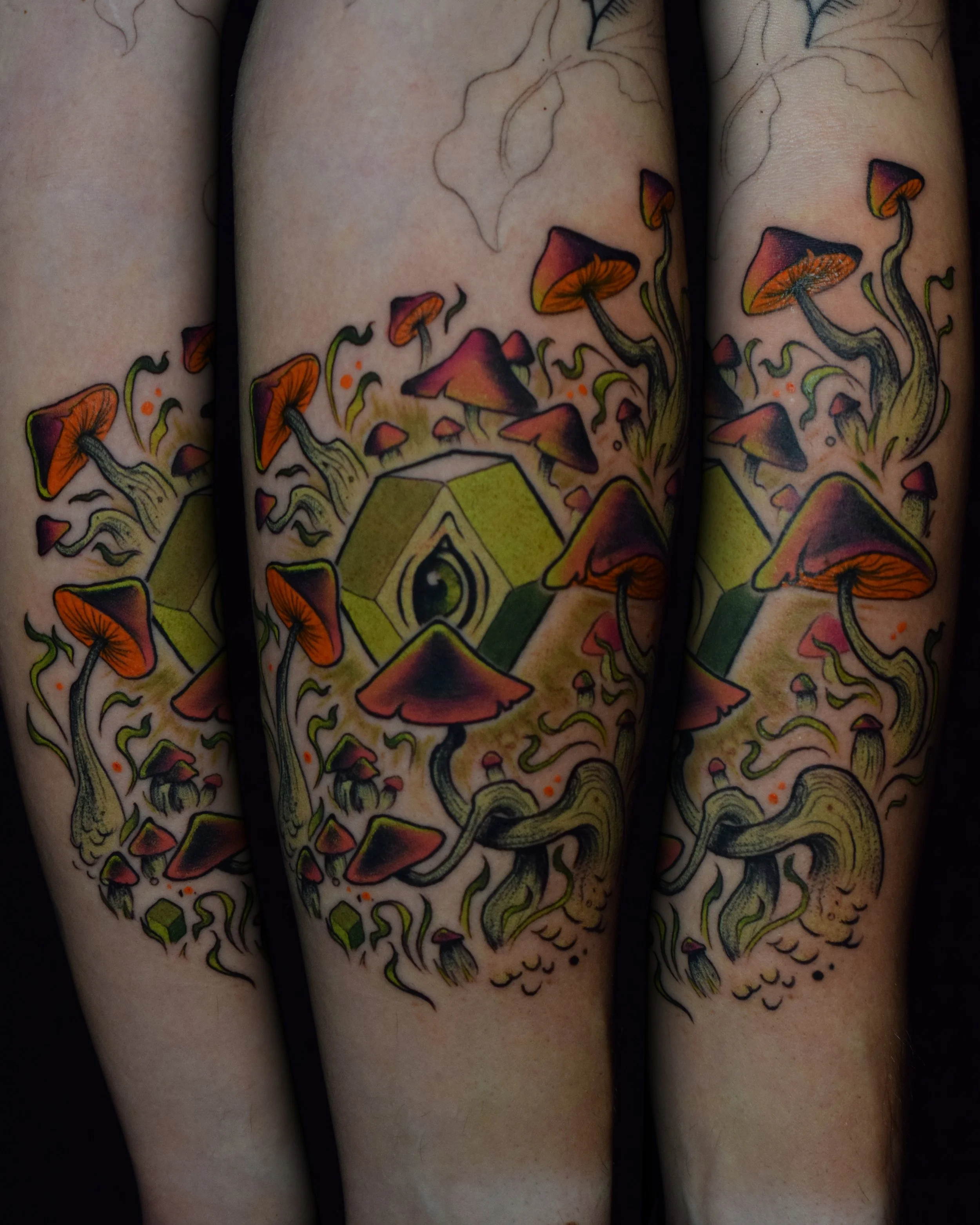 Tattoo of mushrooms, an eye, and a cube on person's arm.