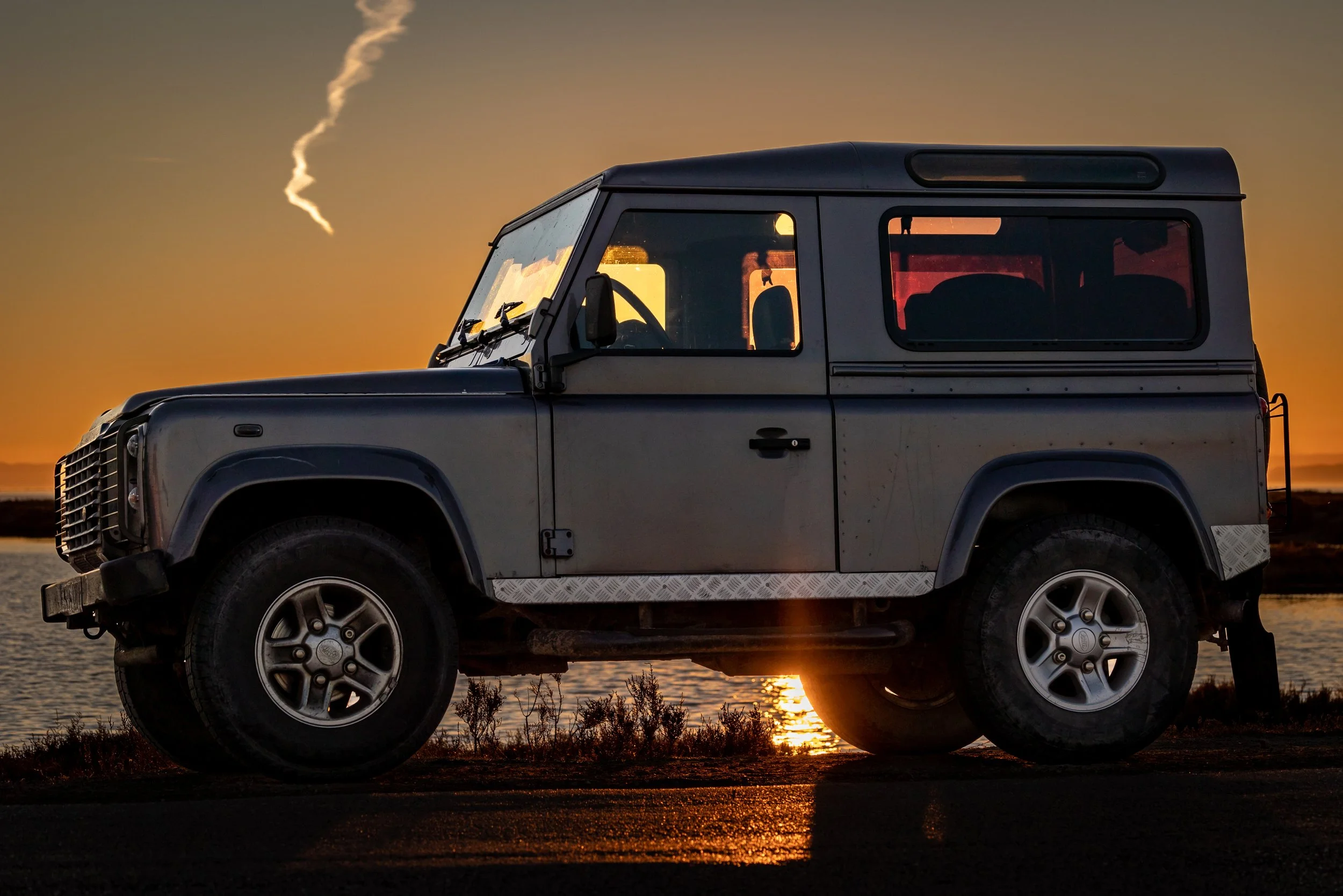 Un vehículo Land Rover en un atardecer junto a un lago.