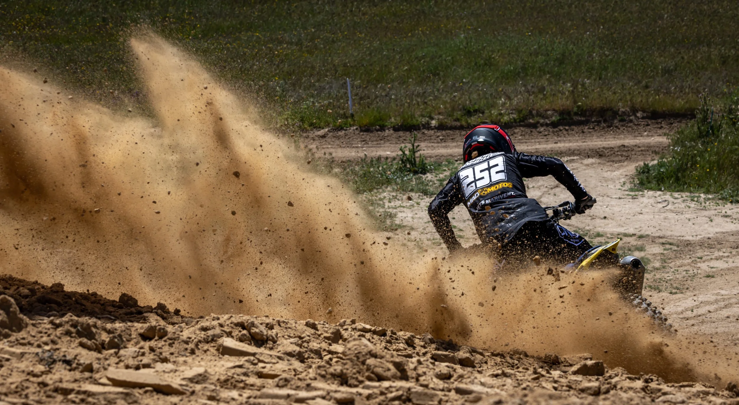 Una persona en una moto de off-road en un terreno arenoso, levantando polvo mientras acelera.