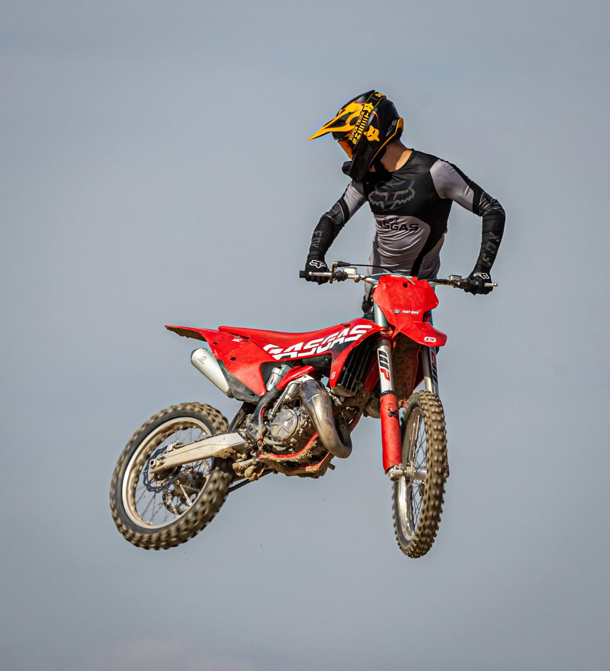 Una persona en una motocicleta de enduro en el aire contra un cielo gris.