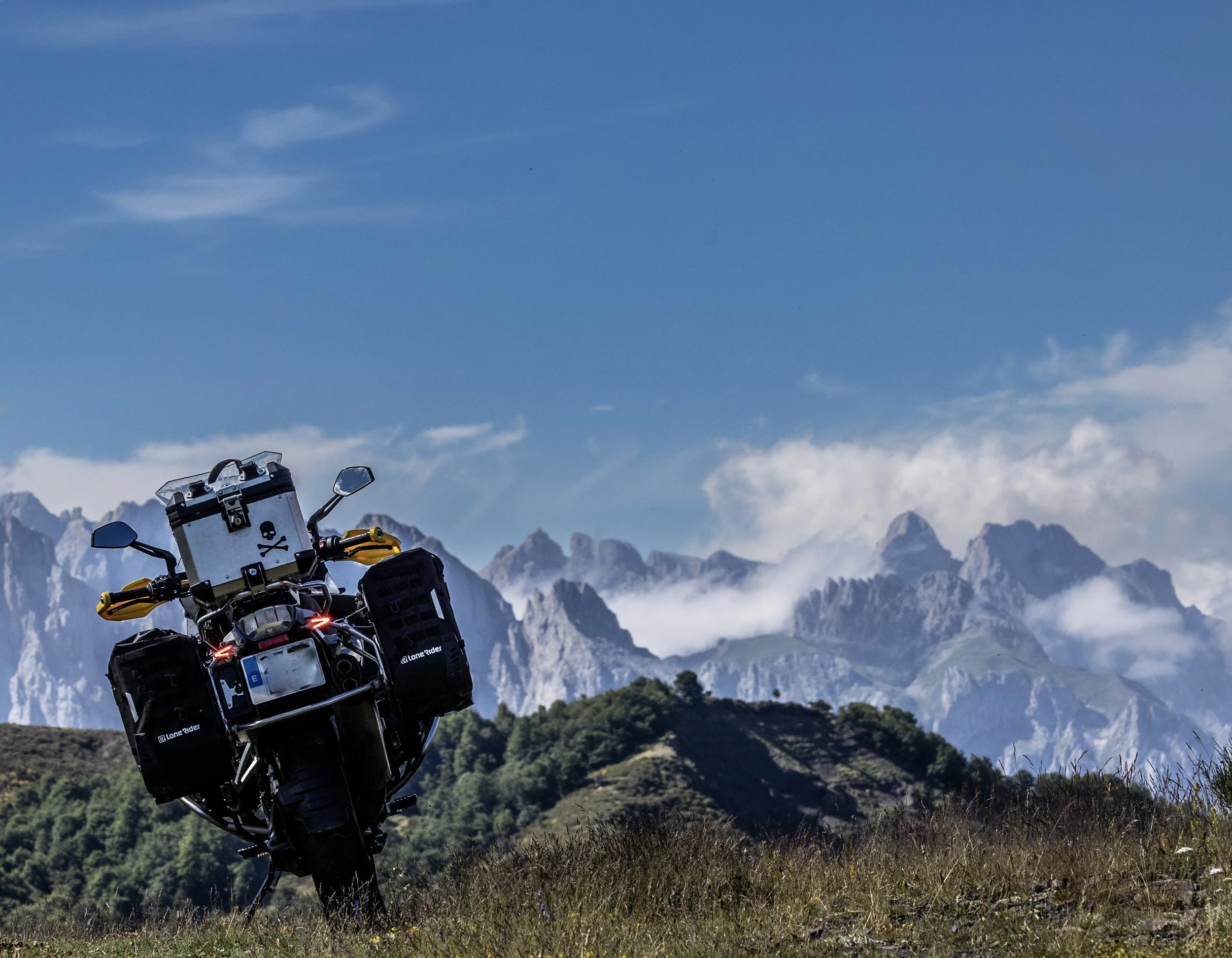 Una motocicleta de aventura en un paisaje de montañas con cielo azul.
