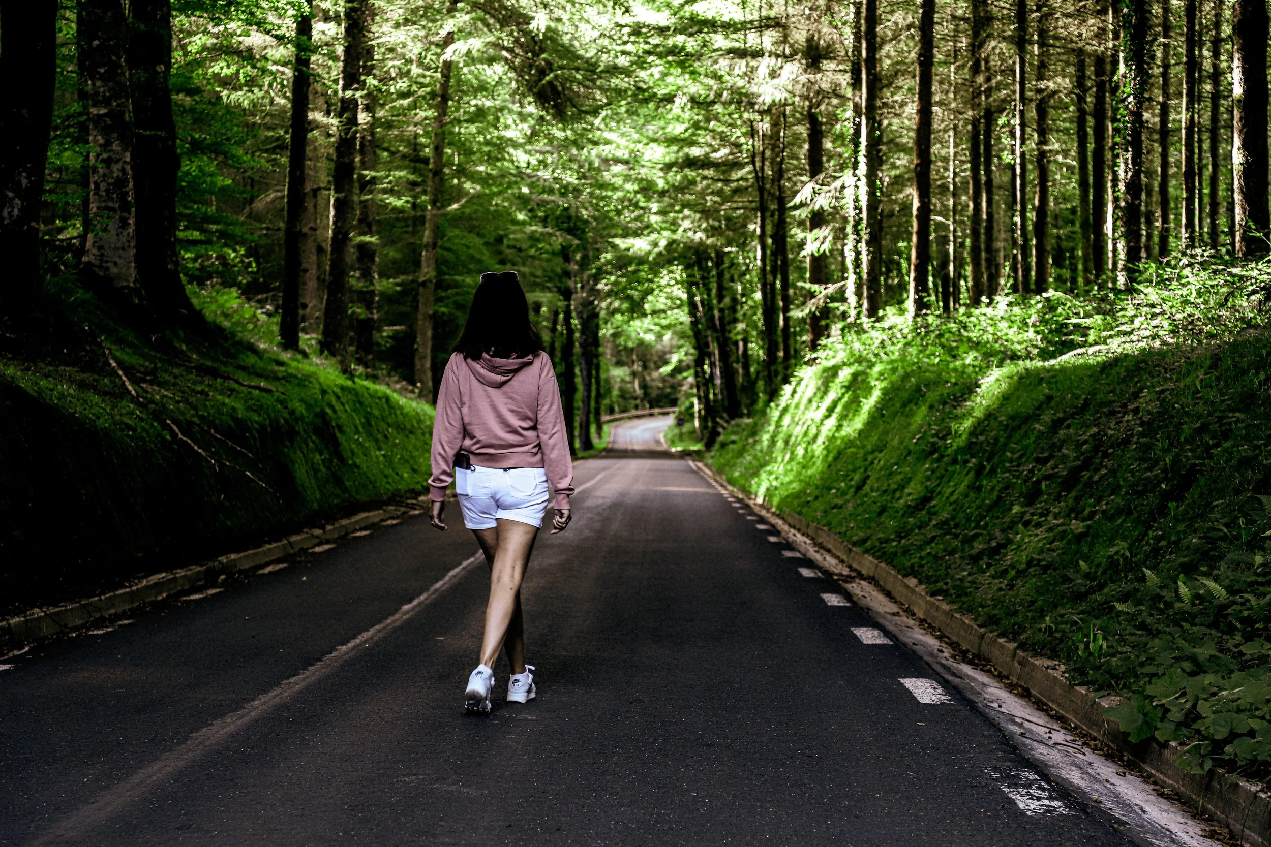 Mujer caminando por un camino en un bosque verde