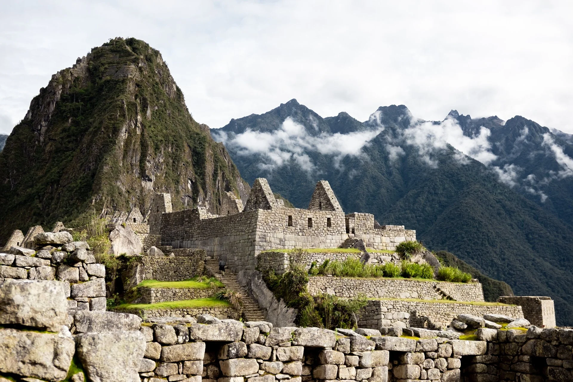 Ancient stone ruins of Machu Picchu set against towering fog-covered mountains with lush green vegetation.