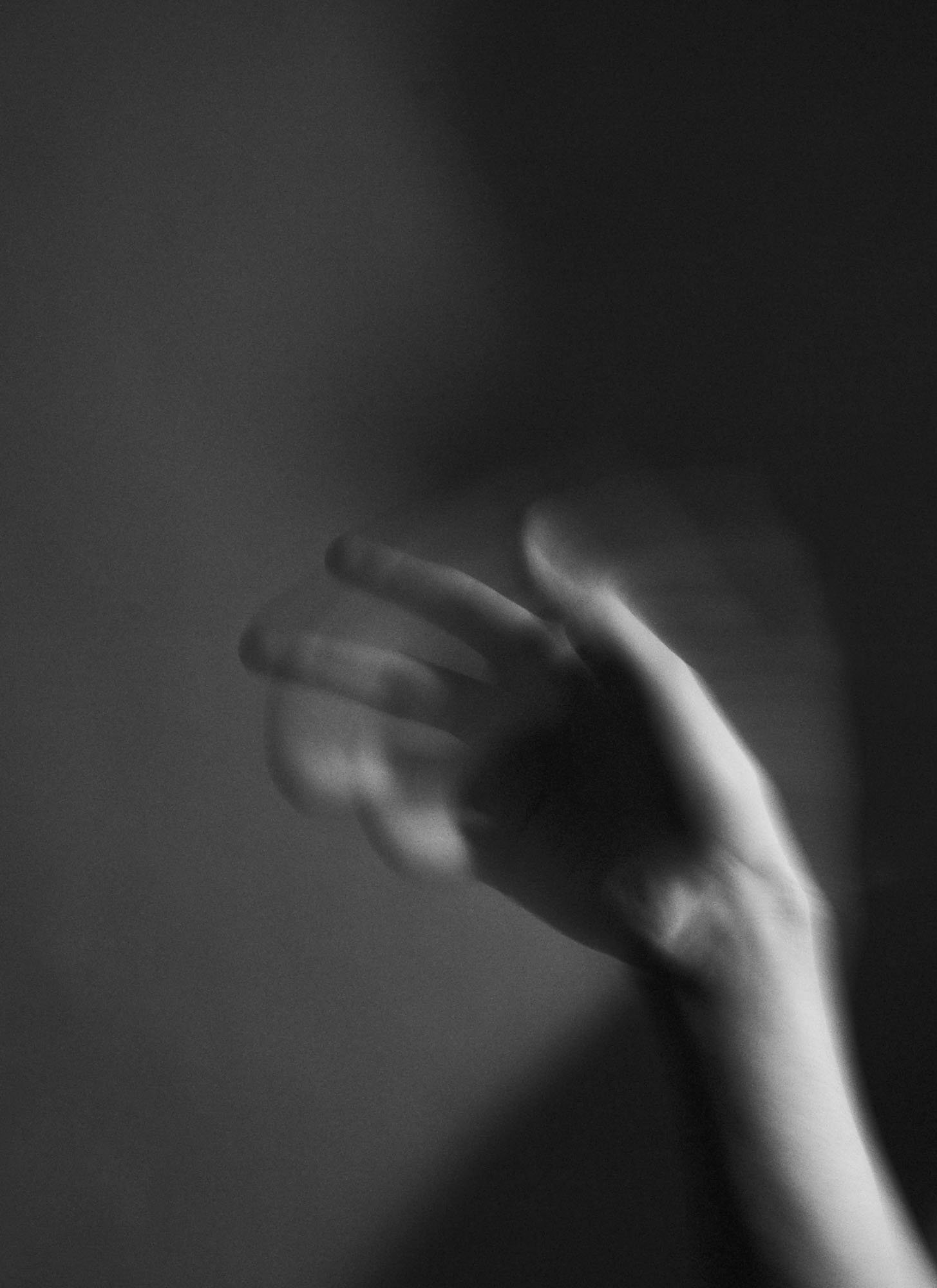 Black and white close-up of a hand with fingers slightly spread, blurred background.