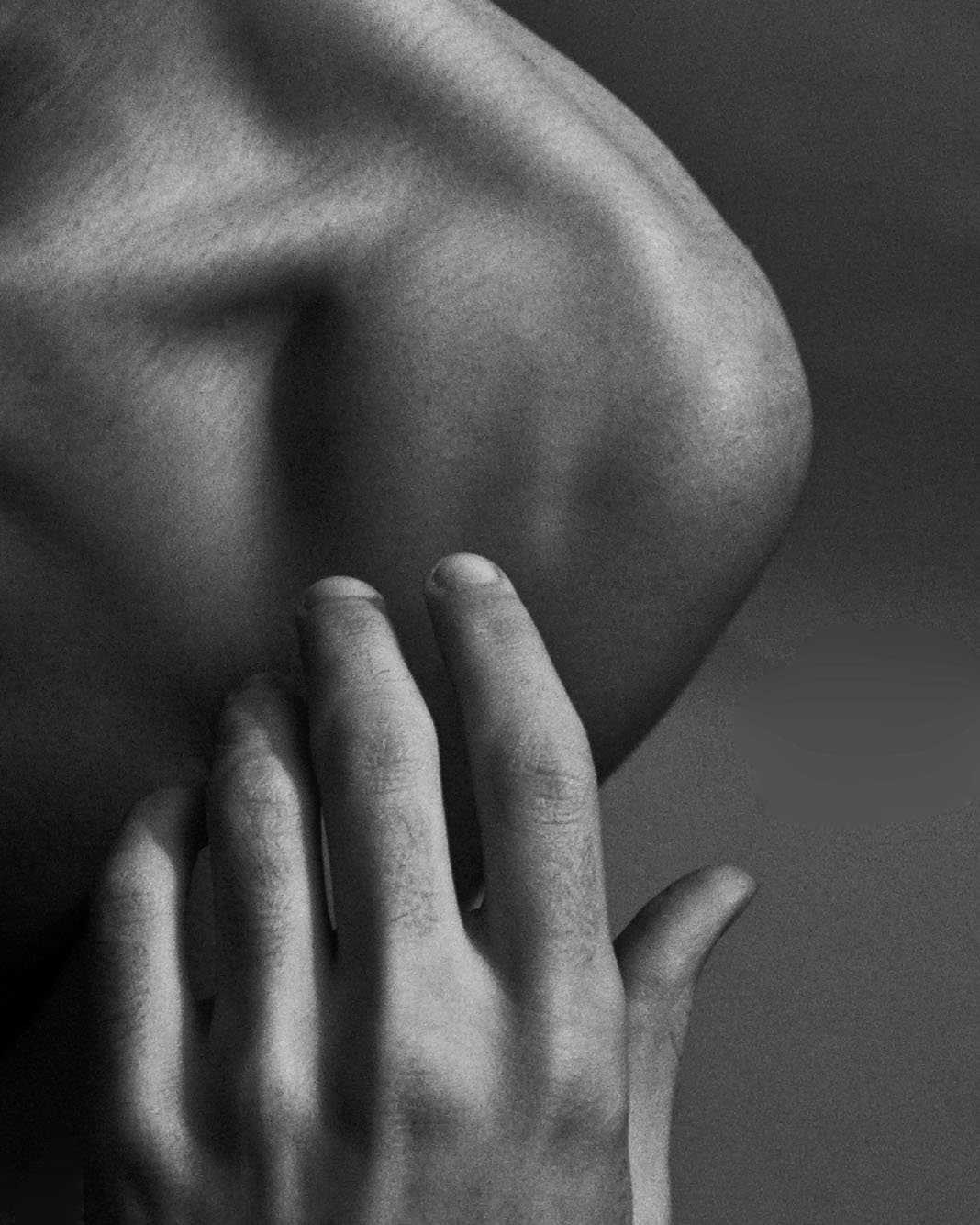 Close-up black and white photograph of a person's hand resting on their face, with fingers touching the lips and thumb near the chin.