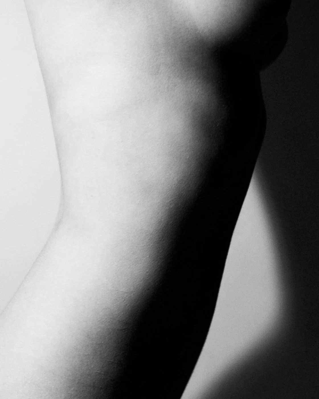 Non-AI human-made digital photograph in black and white of a human arm and shoulder with strong shadows.