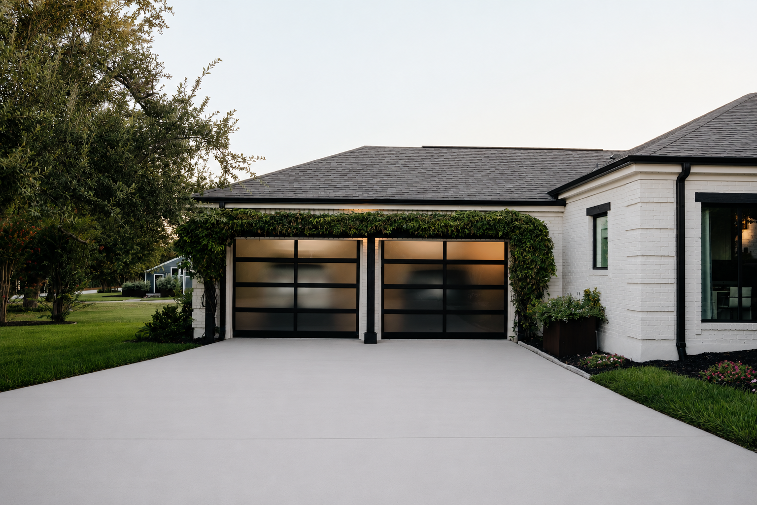 Custom Lakeway home with modern glass garage doors, white brick exterior, and landscaped driveway