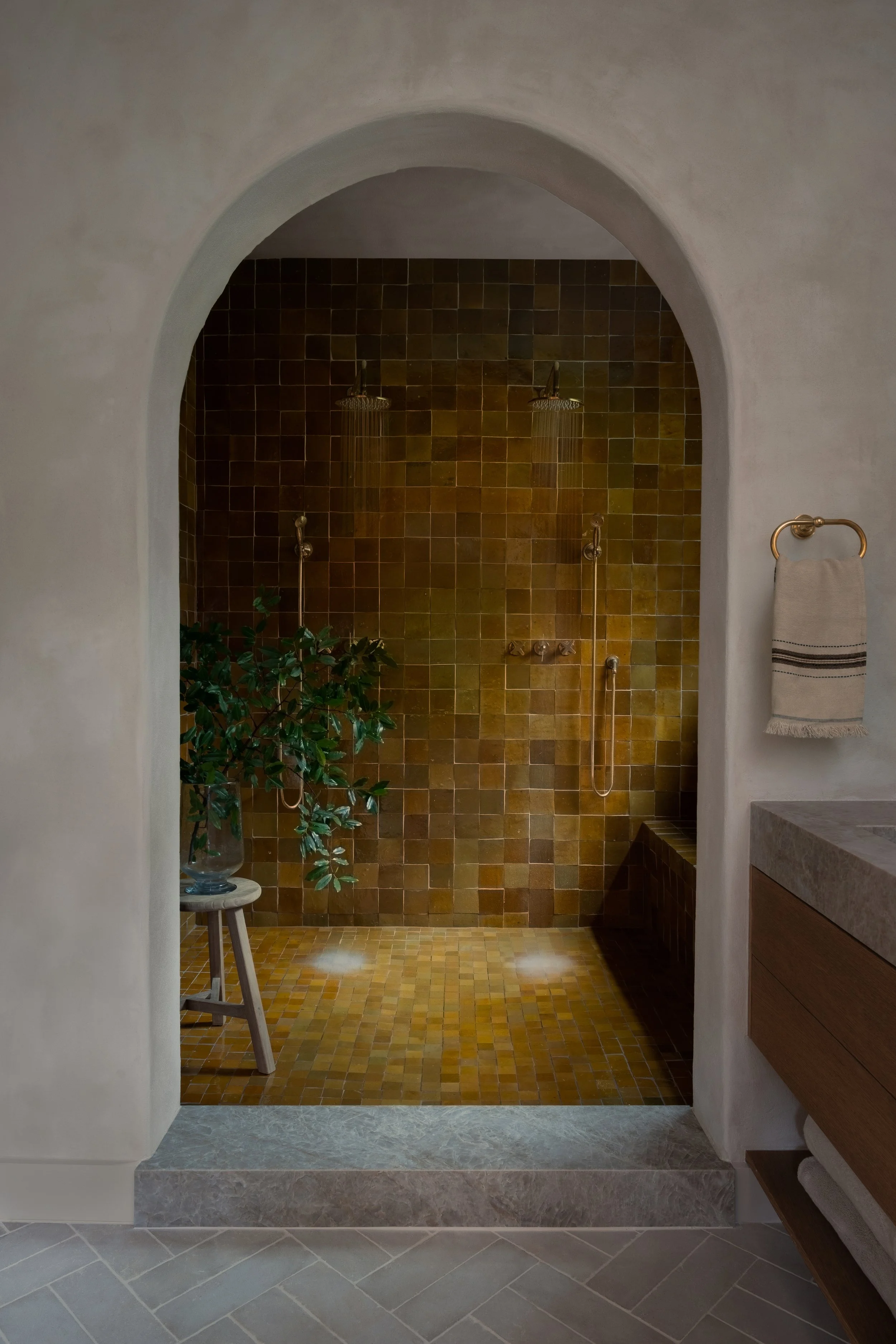 Custom arched shower with handmade-look tile, dual showerheads, brass fixtures, and built-in bench in a Travis Heights primary bathroom remodel